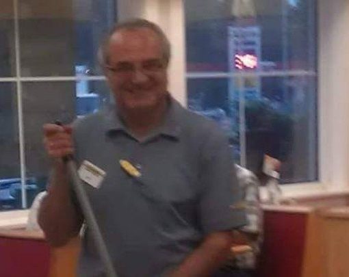 Blurry photo of a man smiling and holding what appears to be a broom